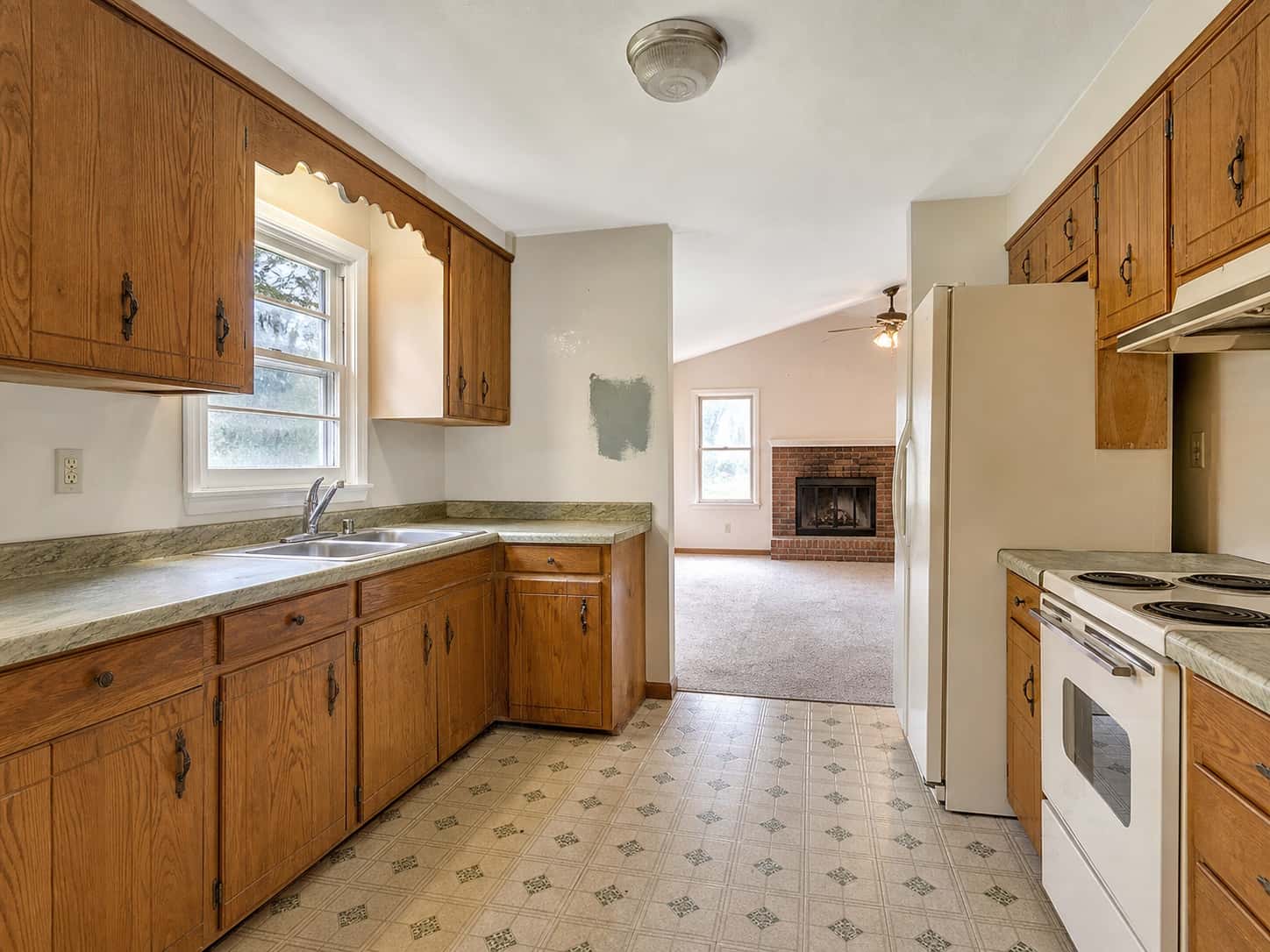Dated kitchen with older cabinets and flooring in need of renovation.